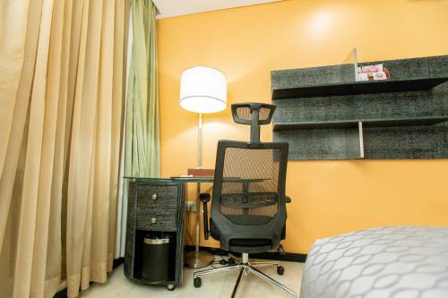 a bedroom with a desk with a chair and a lamp at Best Western Premier Accra Airport Hotel in Accra