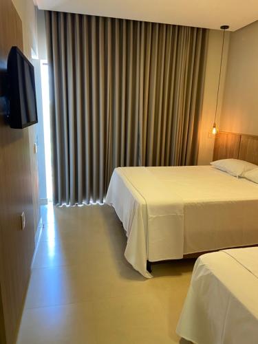 a hotel room with two beds and a flat screen tv at Pousada Viver Capitólio in Capitólio