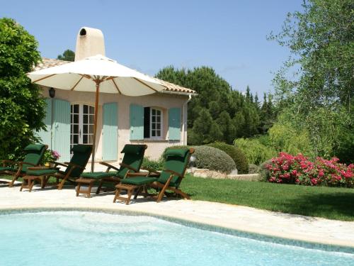 a group of chairs and an umbrella next to a pool at Stunning villa with heated swimming pool air conditioning and large private enclosed garden in Valbonne