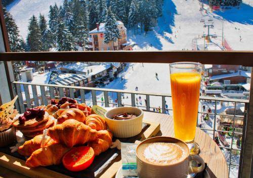 a table with a tray of pastries and a glass of orange juice at Rila Hotel Borovets in Borovets