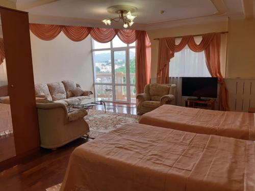 a bedroom with two beds and a living room with a tv at Guest House Lux in Kislovodsk