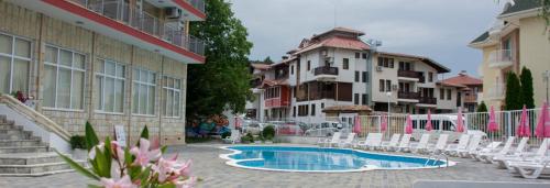 - une piscine dans une cour avec des chaises et des bâtiments dans l'établissement Club Hotel Vedren, à Kranevo