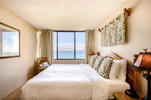 een slaapkamer met een groot bed en een groot raam bij Kaanapali Shores 806 in Kaanapali
