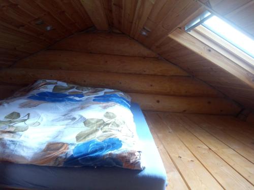 a bed in a small attic with a window at Jugowskie Chatki in Jugów