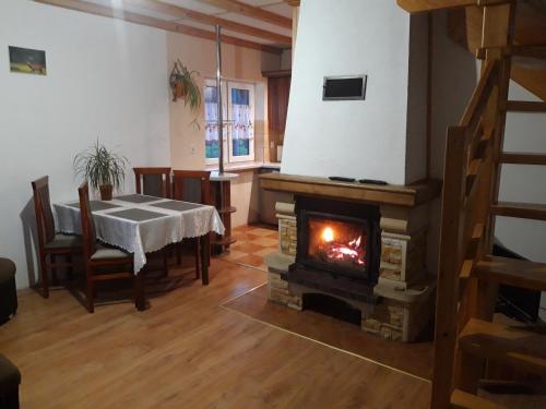 a living room with a table and a fireplace at Domek Regionalny- bliźniak in Baligród