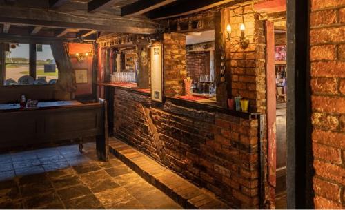 una habitación con una pared de ladrillo y un bar en The Leagate Inn en Coningsby