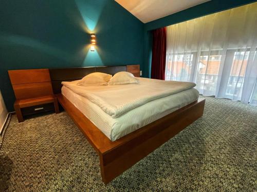 um quarto com uma cama grande e uma parede azul em Hotel Best em Ploieşti