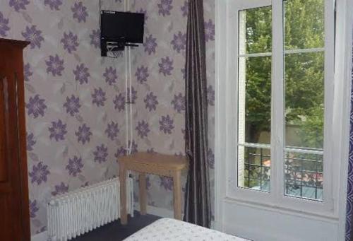 a bedroom with a table next to a window at Ardenn'Hotel in Reims