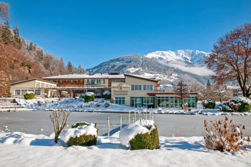a lodge in the snow with mountains in the background at Hotel Vitalquelle Montafon in Schruns-Tschagguns