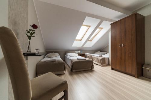 a attic room with two beds and a chair at Dworek Rajska Góra in Wejherowo