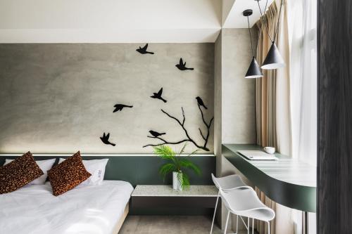 a bedroom with a bed with birds on the wall at Ren House大仁哥文旅 in Taitung City