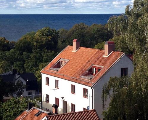 uma casa branca com um telhado vermelho e o oceano em Sköna Hönor Apartments em Visby