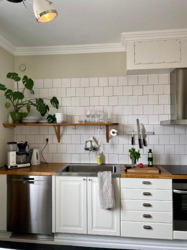 a kitchen with white cabinets and a stainless steel sink at Sköna Hönor Apartments in Visby
