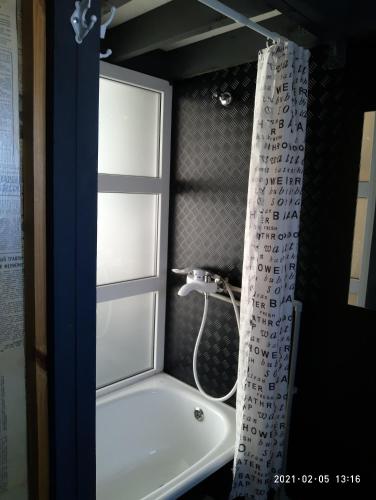 a bathroom with a tub and a shower curtain at Guest House Serena in Chornomorsk