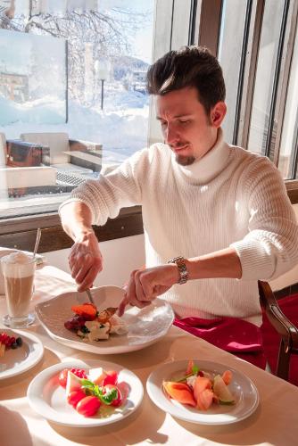 a man sitting at a table with a plate of food at Hotel San Gian in St. Moritz