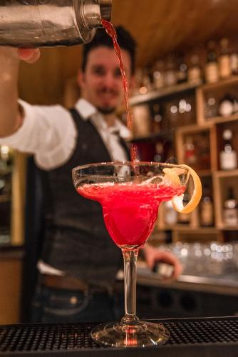 a bartender making a red drink in a martini glass at Hotel San Gian in St. Moritz
