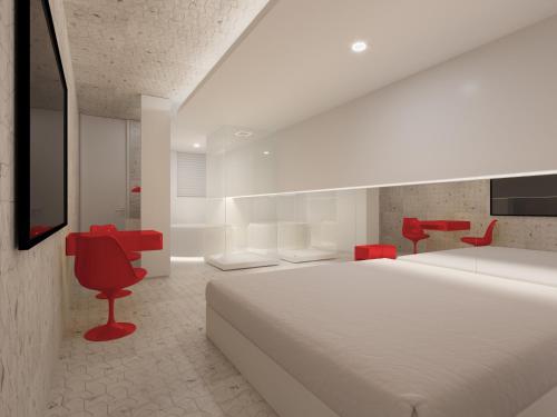 a bedroom with a large white bed and red chairs at Motel Você Que Sabe (Adult Only) in Curitiba