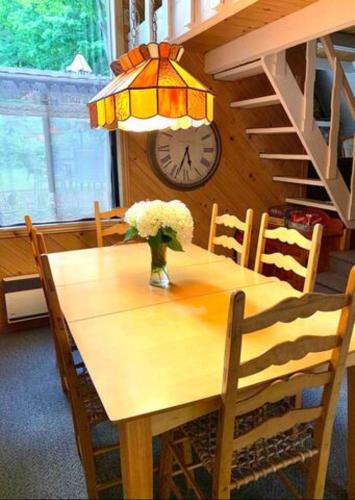 a dining room table with a clock and a vase of flowers at Le Rustique Orford Domaine Cheribourg in Magog-Orford