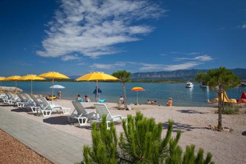 a beach with chairs and umbrellas and people on it at Villa Zarra in Klimno