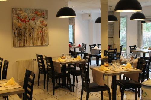 a restaurant with tables and chairs and a painting on the wall at Hôtel Restaurant Aux Genêts d'Or in Mandailles