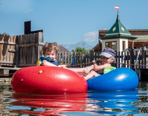 two young boys riding on an inner tube in the water at Alpin Family Resort Seetal in Kaltenbach