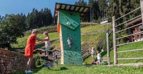 a woman and children on a climbing wall at a playground at Alpin Family Resort Seetal in Kaltenbach
