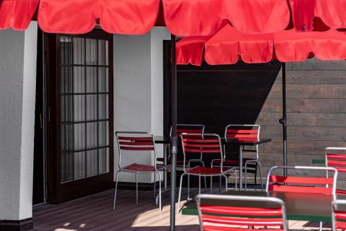 um grupo de cadeiras e uma mesa sob um guarda-chuva vermelho em Experimental Chalet em Verbier