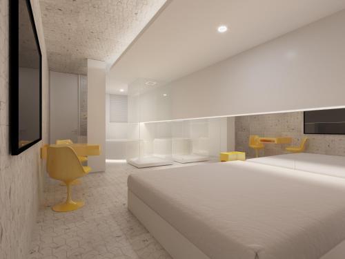 um quarto branco com uma cama grande e uma cadeira amarela em Motel Você Que Sabe (Adult Only) em Curitiba