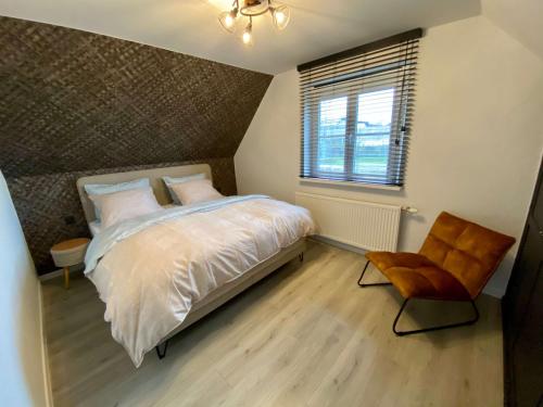 a bedroom with a bed and a chair and a window at Vakantiehuis Cas.tard in Zillebeke