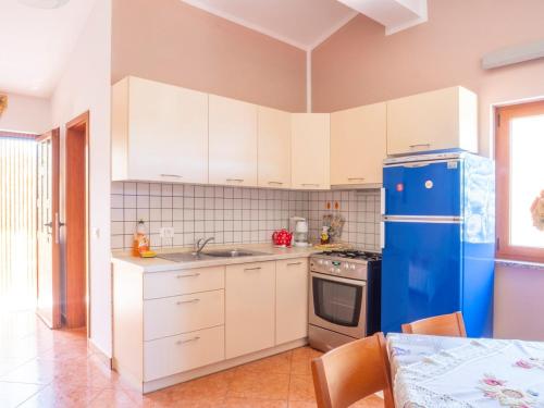 a kitchen with white cabinets and a blue refrigerator at Studio Apartment Gianni in Vižinada
