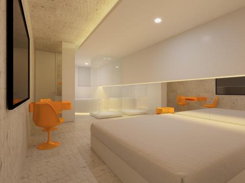 um quarto com uma grande cama branca e uma cadeira em Motel Você Que Sabe (Adult Only) em Curitiba