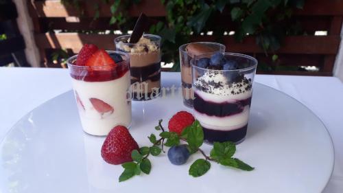 three desserts in glasses on a table with strawberries and blueberries at Apartments at Gostilna Martin in Trbovlje
