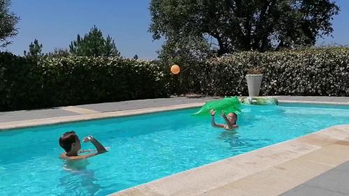 dos niños jugando en una piscina con sombrilla en Vivenda A Nossa Coroa, en Coja