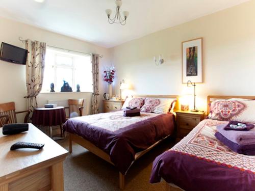 a bedroom with two beds and a table and a window at Wayside B&B in Norwich