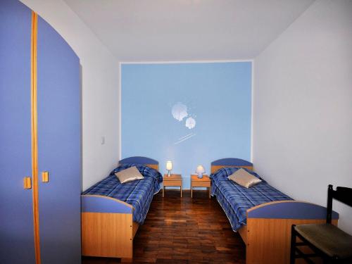 two beds in a room with blue walls at Apartments Paliska in Rabac