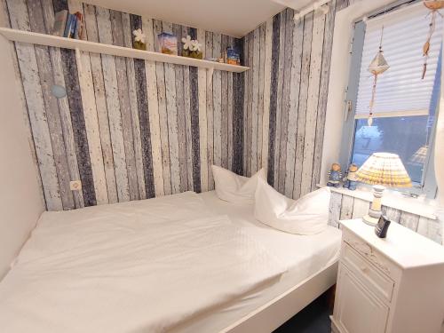 een slaapkamer met een wit bed en een raam bij Ferienwohnung *Fenja* in Norddorf