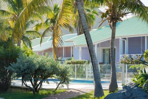a house with palm trees and a swimming pool at Esmeralda Resort - Orient Bay in Orient Bay