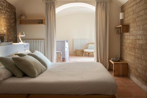 a bedroom with a large white bed with an archway at ECOTurisme Can Buch HOTEL in Sant Aniol de Finestras
