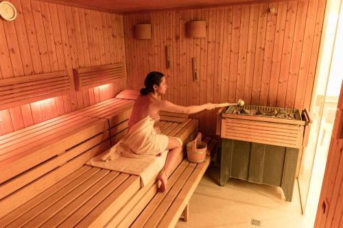 a woman sitting on a wooden bench in a bathroom at Holiday Inn Lübeck, an IHG Hotel in Lübeck
