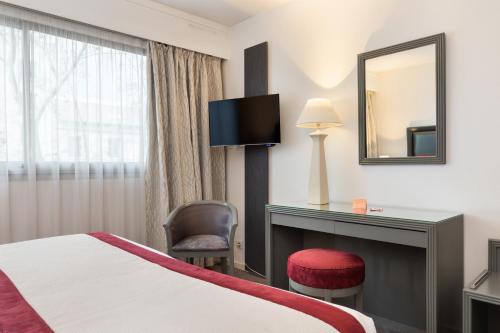 a hotel room with a bed and a desk and a mirror at Hôtel Charlemagne by Happyculture in Lyon