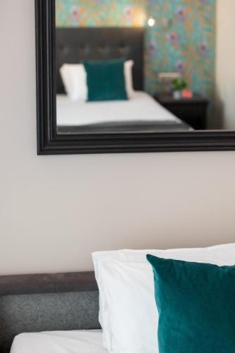a mirror on the wall above a bed with pillows at Hôtel Charlemagne by Happyculture in Lyon