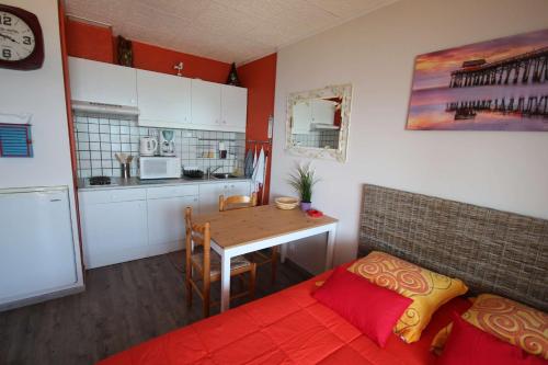 une cuisine avec un canapé rouge et une table dans l'établissement Studio climatise 2 couchages, Wifi, VUE MER directement à PORTIRAGNES PLAGE LXBFM10, à Portiragnes