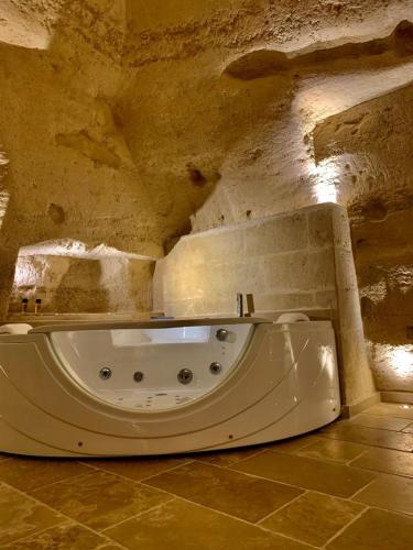 a white bath tub in a room with a stone wall at 5 Elementi Sassi Matera in Matera