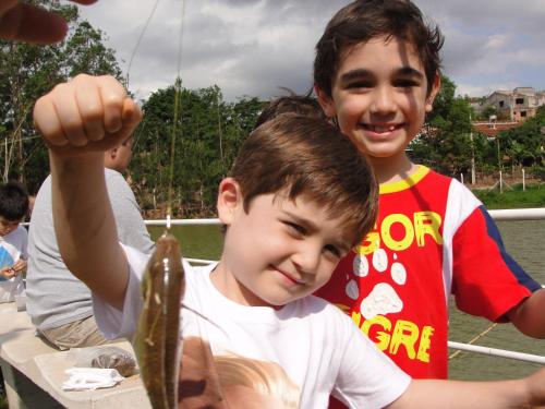 two young boys eating a fish on a boat at Hotel Fazenda Pirâmides in Atibaia
