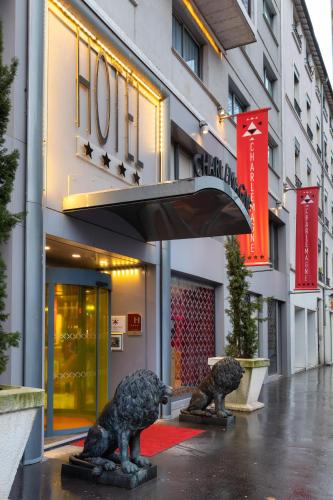 a building with two statues in front of a store at Hôtel Charlemagne by Happyculture in Lyon