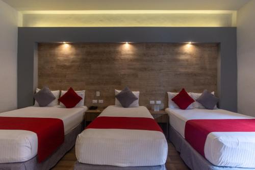 two beds in a room with red and white pillows at Hotel Hidalgo in Querétaro