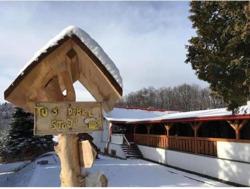 a wooden sign in the snow in front of a building at Penzión Turista in Banská Štiavnica