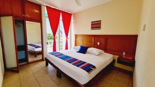 1 dormitorio con 1 cama grande y cortinas rojas en Hotel Machos Mahahual en Mahahual