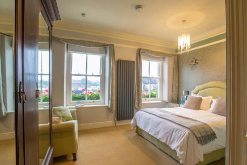 a bedroom with a bed and a chair and windows at The Drovers Bed and Breakfast in Llandovery