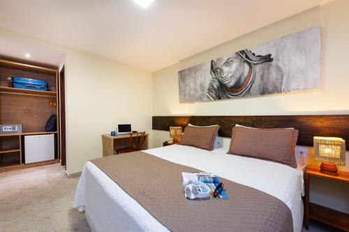 a bedroom with a large bed and a painting on the wall at Pousada Bahia Bacana in Morro de São Paulo